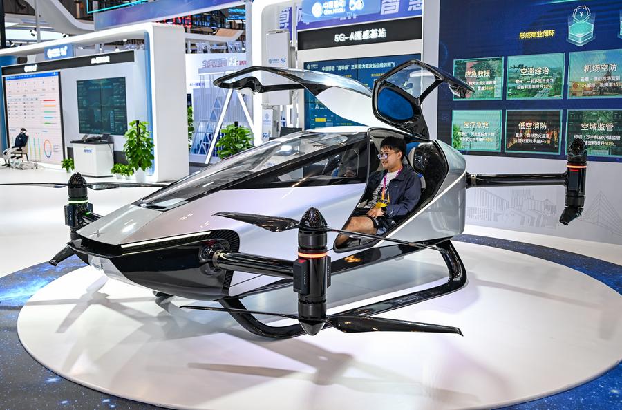 Um jornalista senta-se em uma aeronave elétrica de decolagem e pouso verticais (eVTOL) no local da Exposição Mundial da Indústria Inteligente 2025, em Chongqing, sudoeste da China, em 4 de setembro de 2025. (Xinhua/Wang Quanchao)