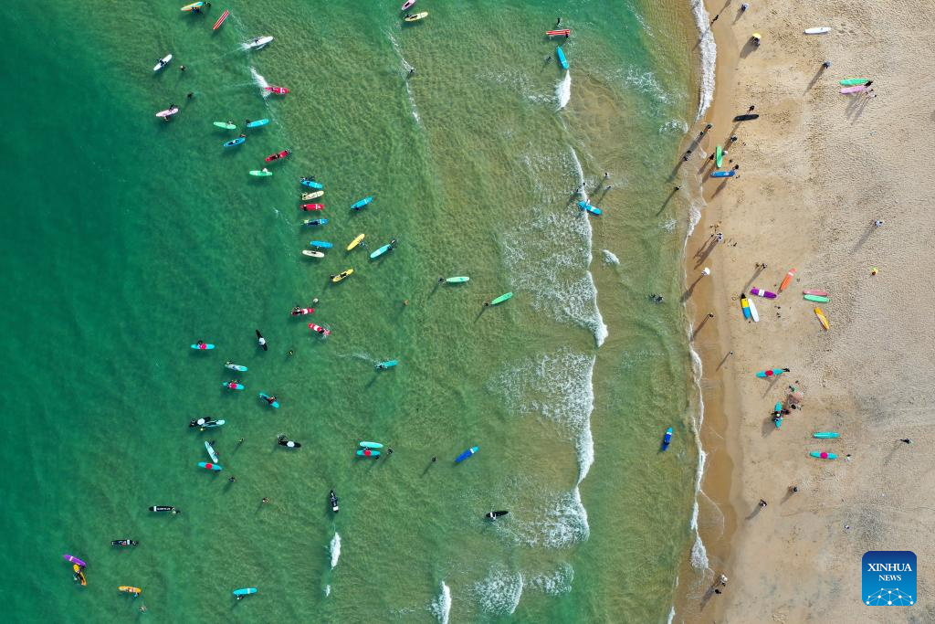 Turistas surfam na Baía Riyue, em Wanning, na Província de Hainan, sul da China