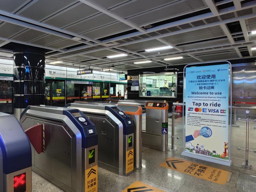 Foto de 11 de outubro de 2025 mostra um banner promovendo pagamento sem contato com os principais cartões bancários internacionais ao lado de catracas automáticas em uma estação de metrô em Guangzhou, Província de Guangdong, sul da China. (Metrô de Guangzhou/Handout via Xinhua)