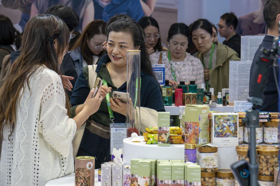 Uma visitante se inteira sobre produtos de rosas, do Irã, na área de exposição de bens de consumo da 8ª Exposição Internacional de Importação da China (CIIE), em Shanghai, leste da China, em 7 de novembro de 2025. (Xinhua/Ding He)
